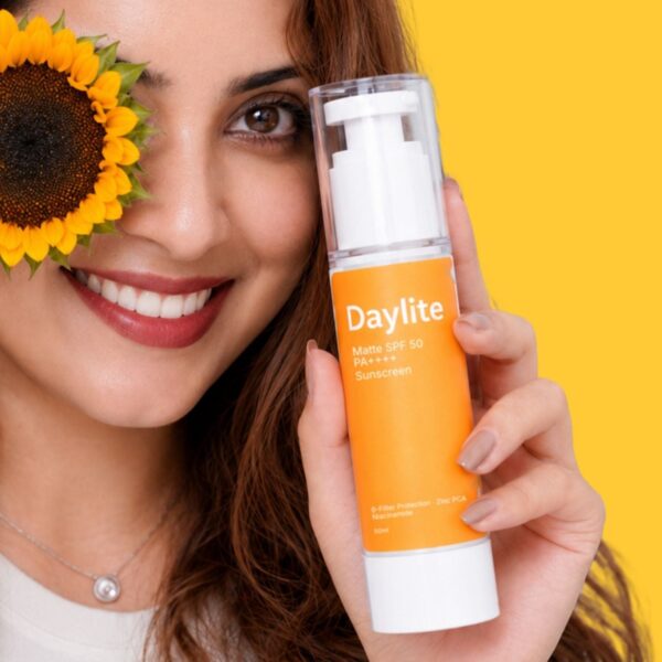 Woman holding Daylite SPF 50+ sunscreen beside her face, with a sunflower, on a yellow background